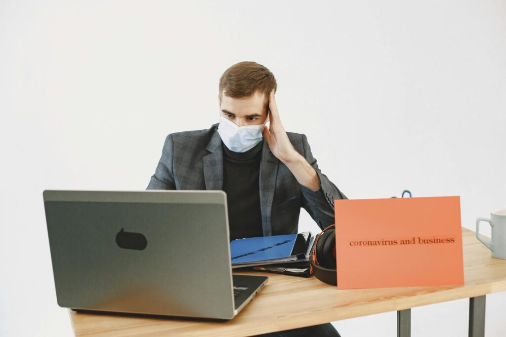 Frustrated Man in Face Mask Working on Laptop